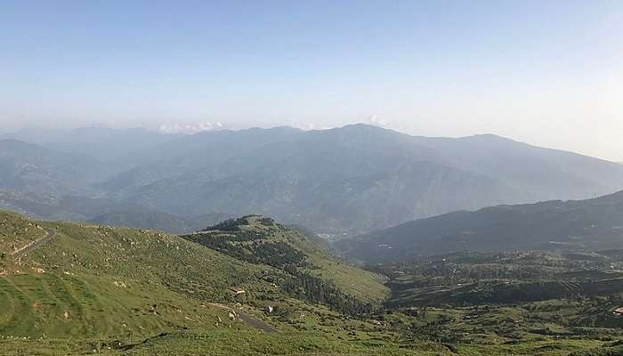 The countryside with rolling hills, thickets of trees, and pastures of green