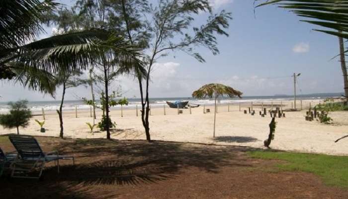 A serene view of Utorda Beach with clear waters and palm leave umbrella made for tourists