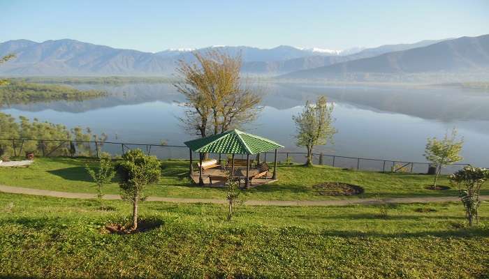 Wular Lake with the view of Kashmiri boats in the water and mountains on the opposite side. 