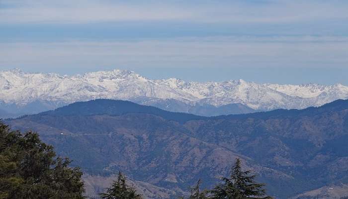 Snow-laden peak of Mahasu with trekkers ascending the trail