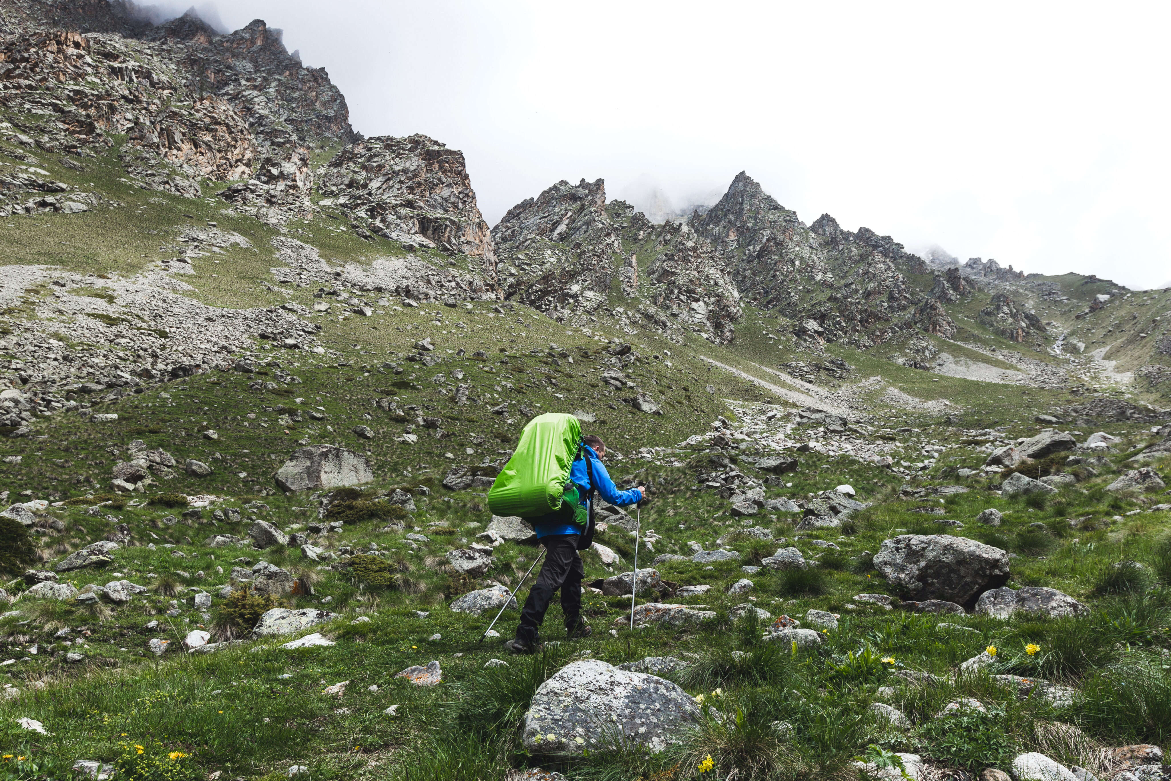 Tourist with large backpack hiking in the mountains, around high